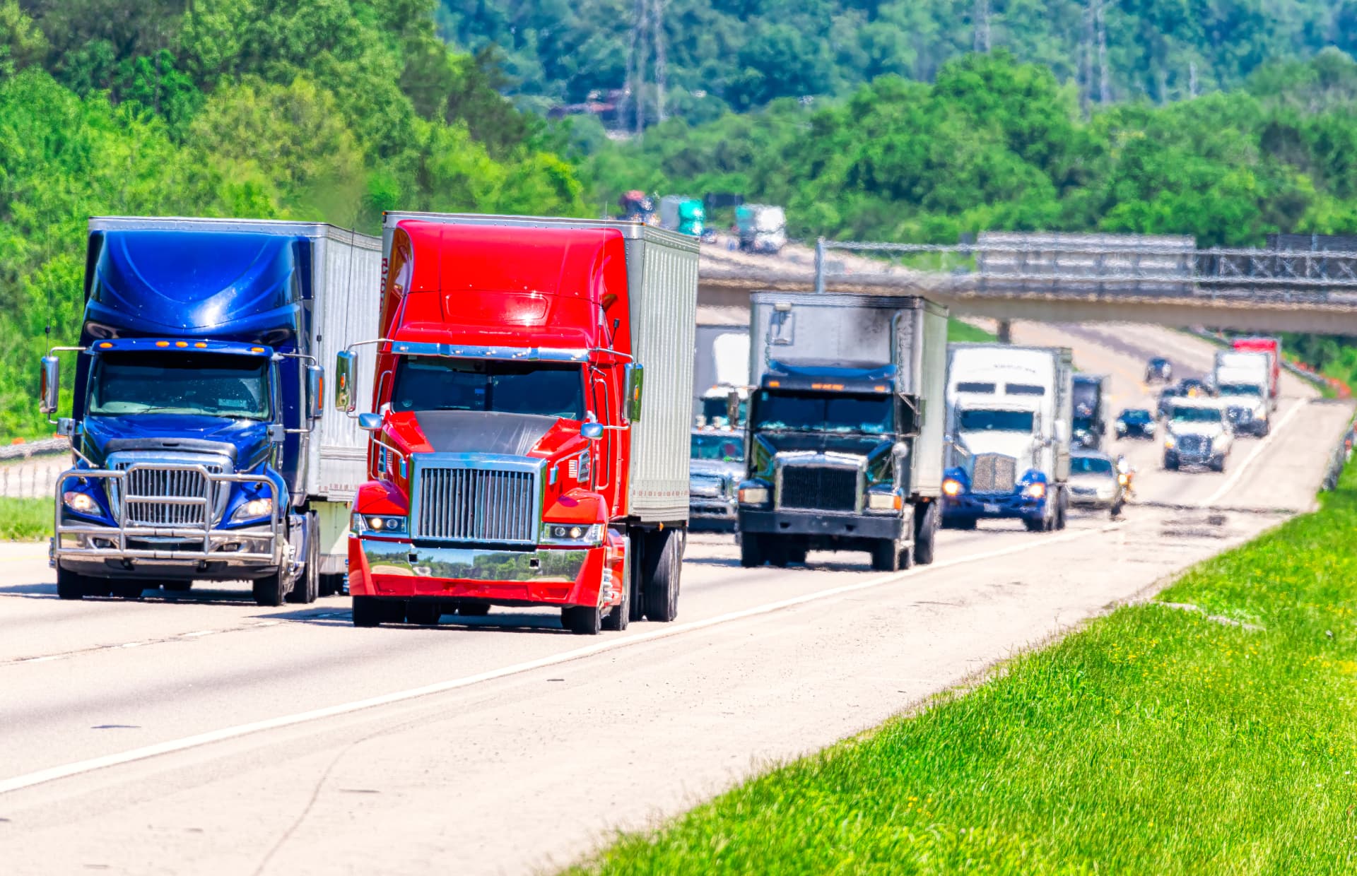 Colorful semi-trucks traveling a green interstate corridor in daylight
